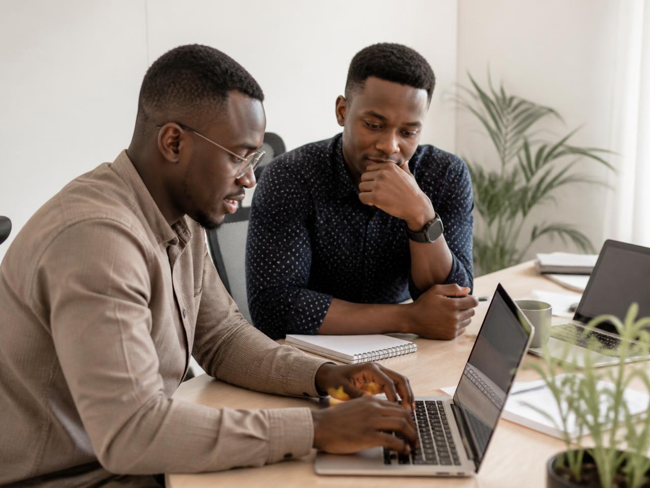 Two software engineers reviewing code together at a bright office desk